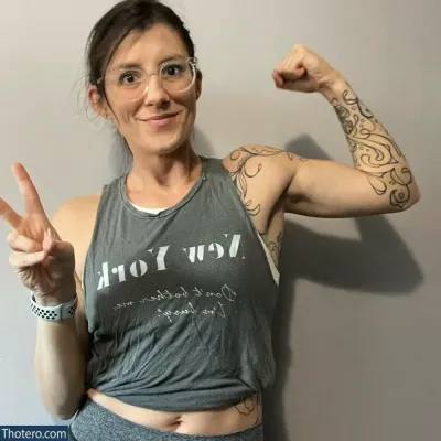 themrsnextdoor2.0 - woman with glasses and a tank top showing a peace sign