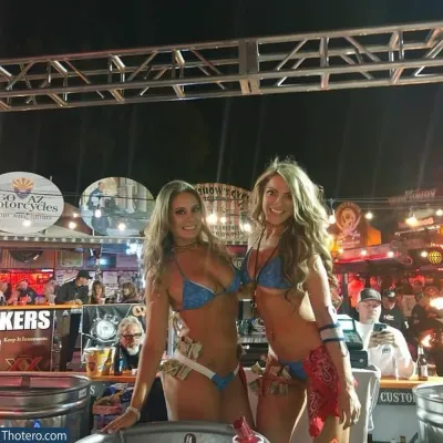 Karin Noelle - two women in bikinis standing next to a bar with a beer