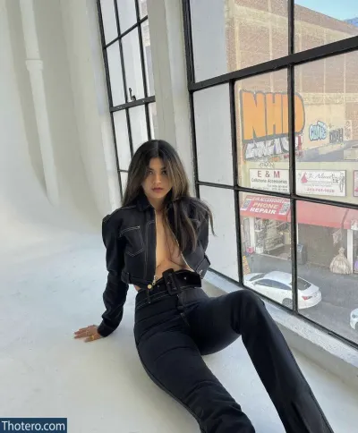 Sara Echeagaray - woman sitting on a window ledge in a black jacket and jeans