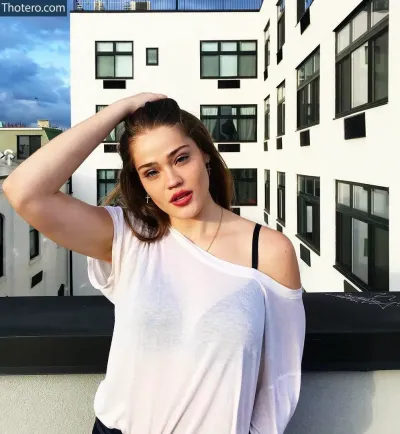 Laney DeGrasse - woman in white shirt posing on a balcony with buildings in the background