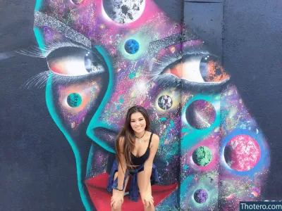 Marina Yamaguti - woman sitting on a red chair in front of a colorful mural