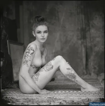 aiclaf - woman with tattoos sitting on a bed in a room