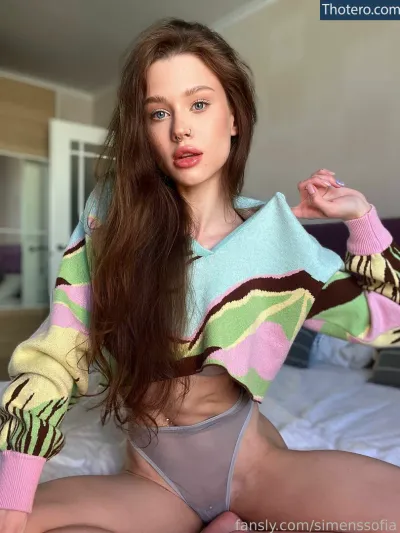 SimensSofia - woman in a colorful sweater sitting on a bed