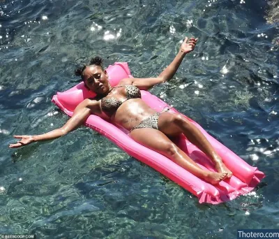 Melanie Brown - woman in a bikini laying on a pink inflatable raft in the water