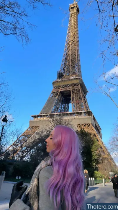 Jessu - a woman with pink hair standing in front of the eiffel tower