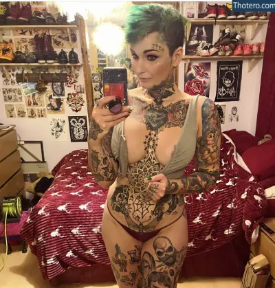 Heather McLean - tattooed woman taking a selfie in her bedroom with a phone