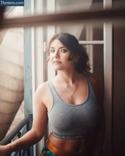 Eleonore Costes - woman in a gray tank top standing by a window