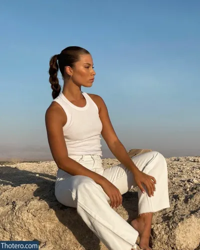 Yeela Frumkin - woman sitting on a rock in white pants and a white tank top