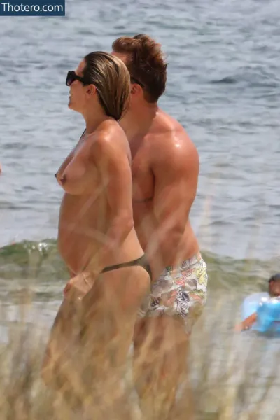 Zoe Hardman - pregnant couple walking on beach with children in background