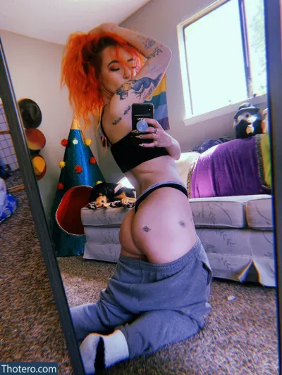 Indoor_wilding - woman with red hair and tattoos taking a selfie in a mirror