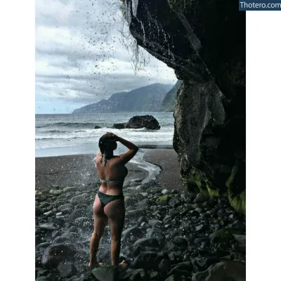 Zoesimplement - there is a woman standing on a beach with a waterfall coming out of the water