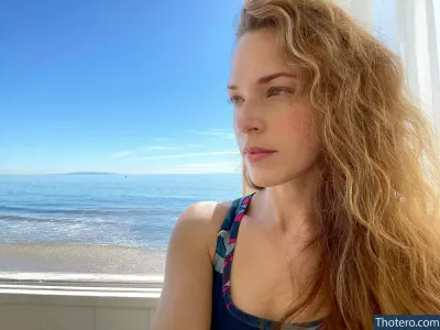 Amanda Righetti - woman with long hair looking out of a window at the beach