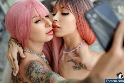 shameless_sg - two women with pink hair are kissing and taking a picture
