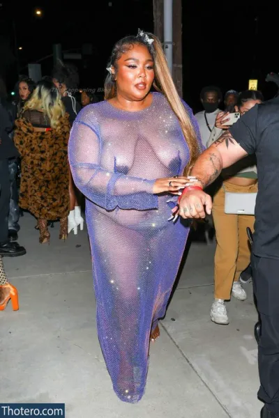 Lizzo - a woman in a purple dress is walking down the street