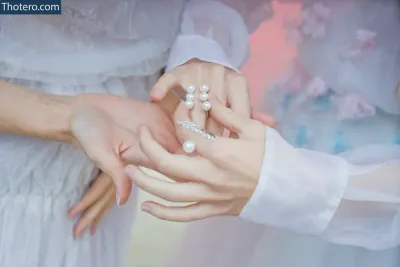 Anastasiya Ukolova - bride and groom holding hands with pearls and wedding rings