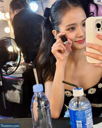 Jisoo - woman in a black dress holding a cell phone and looking at her phone