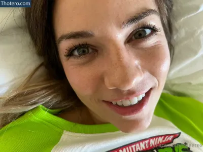 Ryleerex - smiling woman in green and white shirt laying in bed with a donut