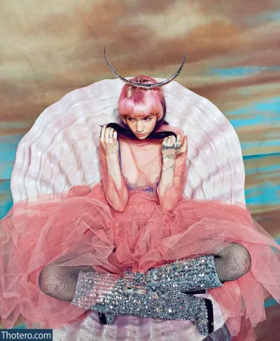 Grimes - woman in a pink dress sitting on a chair with a large horn