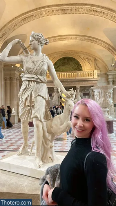 Jessu - woman with pink hair standing in front of a statue