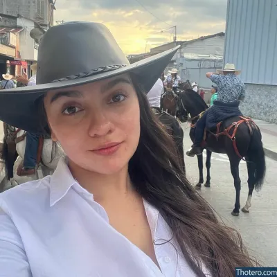 lamartinezruiz - woman wearing a black hat and white shirt standing in front of a group of horses