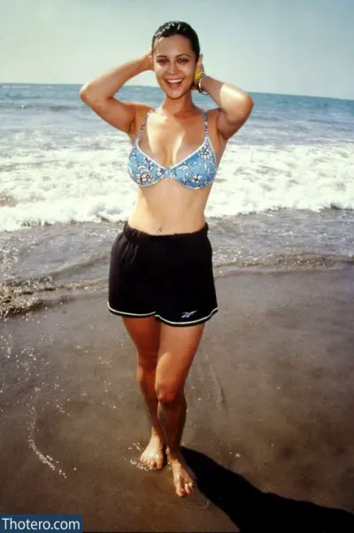 Catherine Bell - woman in a bikini and black skirt standing on the beach