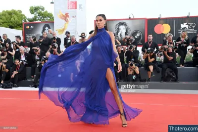 Melissa Satta - a woman in a blue dress walks on a red carpet