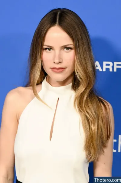 Halston Sage - a woman with long hair wearing a white top and black pants