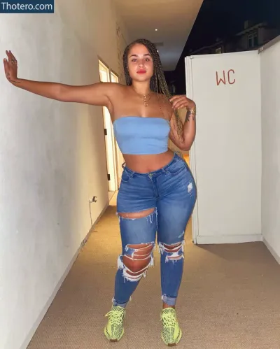 Janae Girard - woman in a blue top and ripped jeans posing for a picture