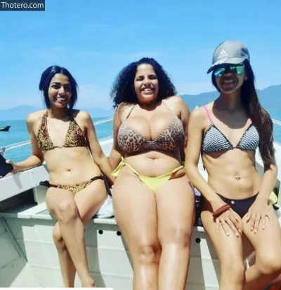 Mayla Coimbra - three women in bikinis sitting on a boat in the water