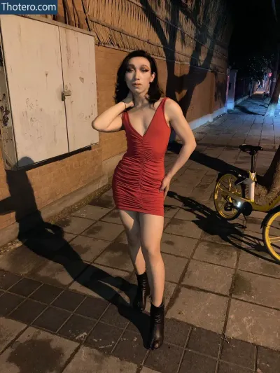 JGSTH4 - woman in a red dress standing next to a bicycle