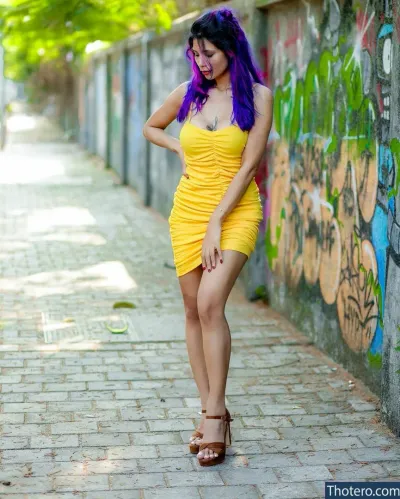 Annie Sharma - woman in a yellow dress posing in front of a graffiti wall