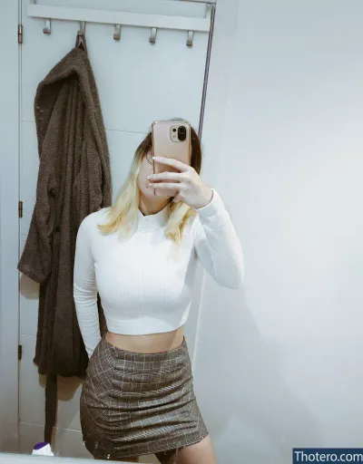 mineofyours - blond woman taking a selfie in a bathroom mirror with a phone