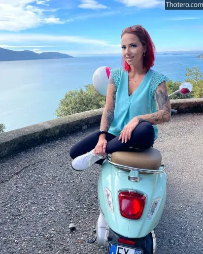 Nina Devil - woman sitting on a scooter with a view of the ocean