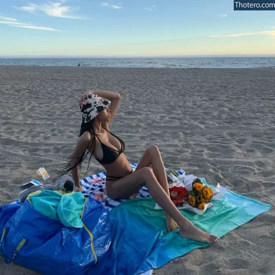 Kira Imani - woman sitting on a towel on the beach with a towel on her head