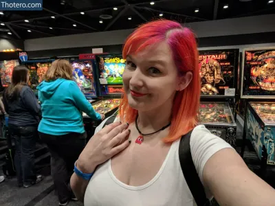 Kinsey Burke - woman with bright red hair standing in front of pinball machines