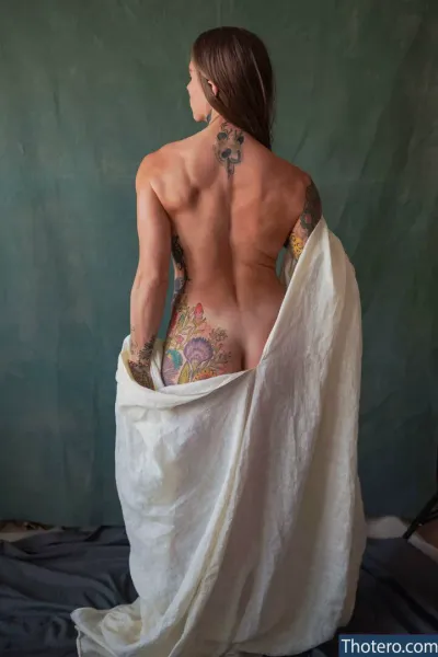 Ella Anne Kociuba - woman with tattoos on her back and a sheet draped over her
