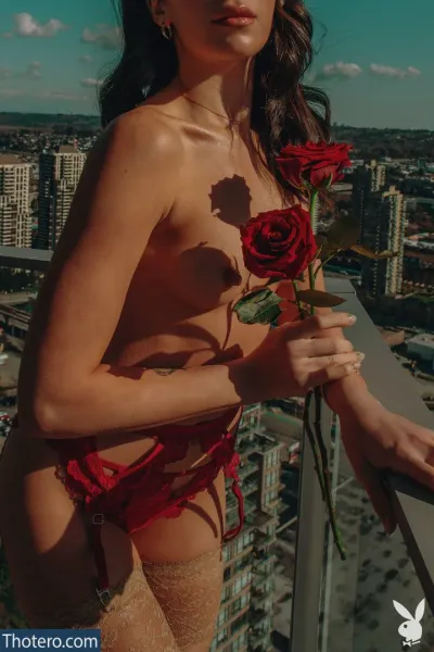 Xris Kovtos - woman in a red bikini holding a rose on a balcony