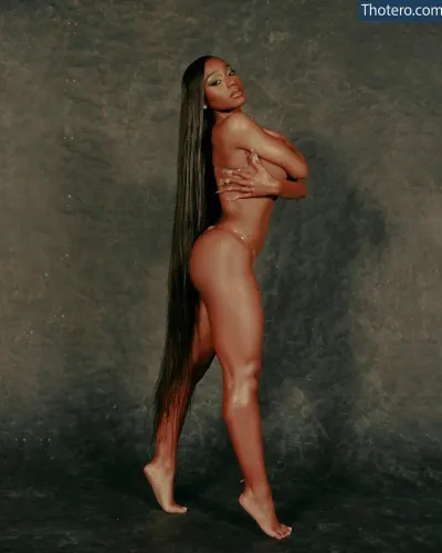 Normani - a woman with long hair posing in a studio with a gray background