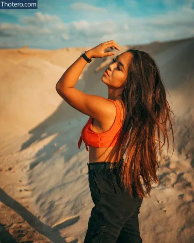 Camii_tg - woman in an orange top standing in the sand