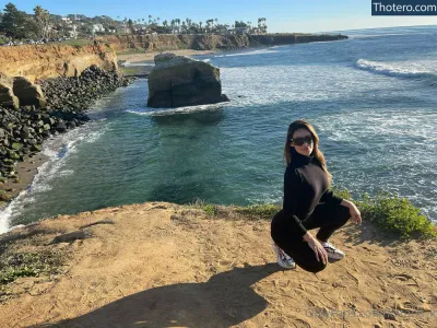 katana_k - woman in black shirt and sunglasses sitting on a cliff overlooking the ocean
