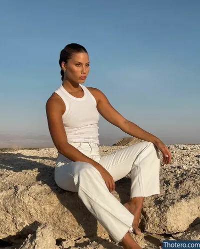 Yeela Frumkin - woman sitting on a rock in white pants and a white tank top