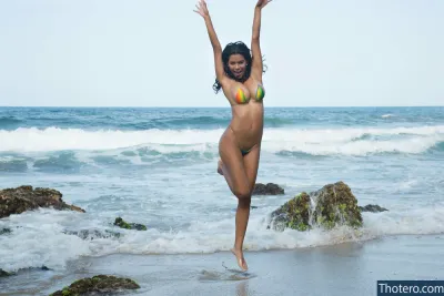 Angie Rivas -  woman in a bikini jumping in the air on the beach
