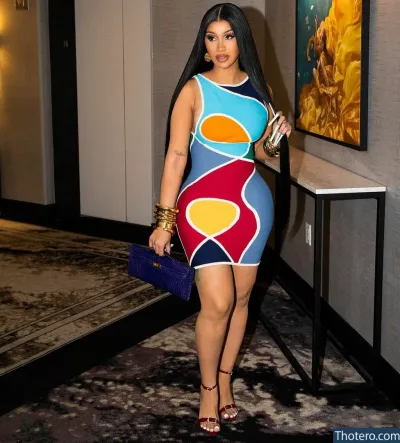 Cardi B - dressed in a colorful dress and heels standing in a hallway