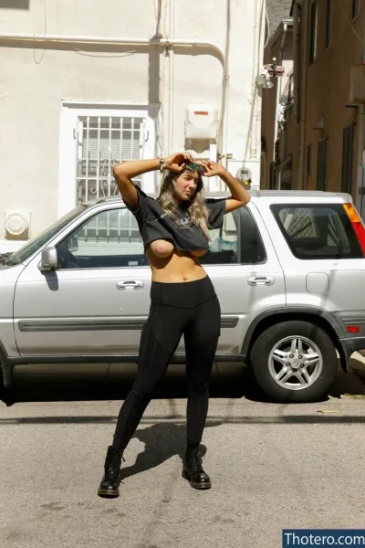 Maddie Crump - woman in black top and black leggings standing in front of a silver car