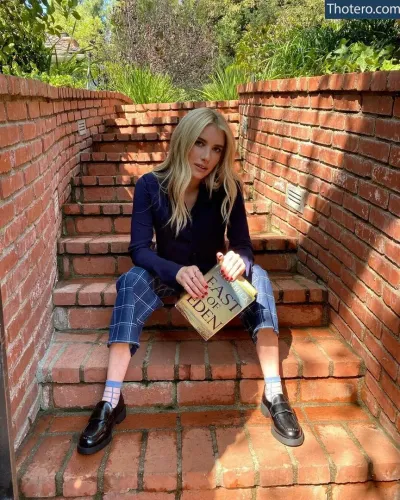 Emma Roberts - blond woman sitting on brick steps holding a book