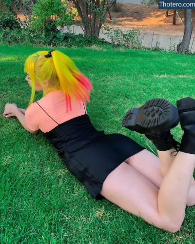 Cindy Paola - with bright yellow hair laying on the grass in a park
