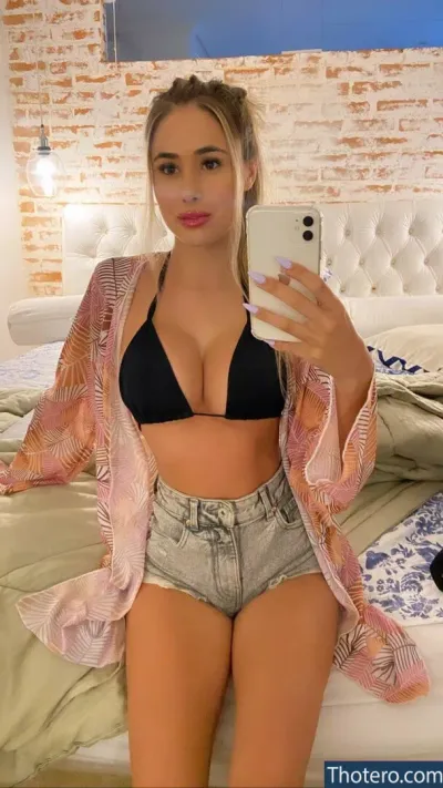 Myara Bigo - woman in a bikini top taking a selfie in a bed