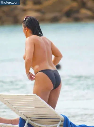 Jessie Wallace - there is a woman in a bikini sitting on a beach chair