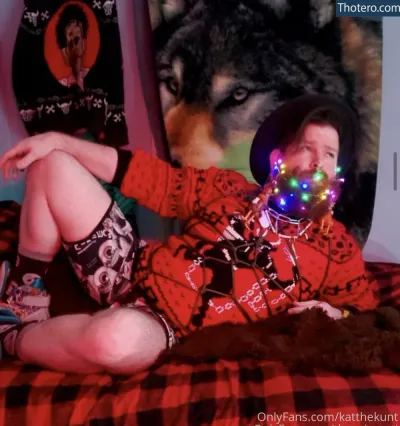 KatTheKunt - man in red shirt laying on bed with christmas lights on his mouth