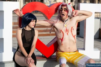 Emily_Cos - they are posing for a picture with a heart sign in the background